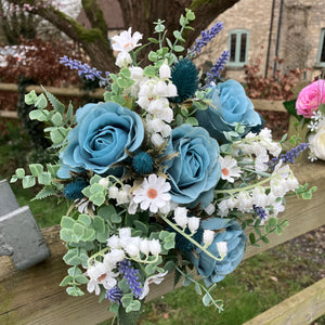 A wedding bouquet of white and teal flowers and foliage