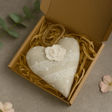 Heart-shaped decorative item with lace and a flower in a brown box on a gray surface.