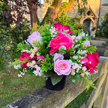 a graveside pink and cream memorial arrangement in black plastic pot