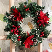 An artificial pine christmas wreath with holly and poinsettia