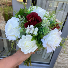 A brides bouquet of deep burgundy and ivory faux flowers