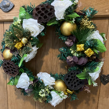 An artificial pine christmas wreath with pale gold and ivory decorations