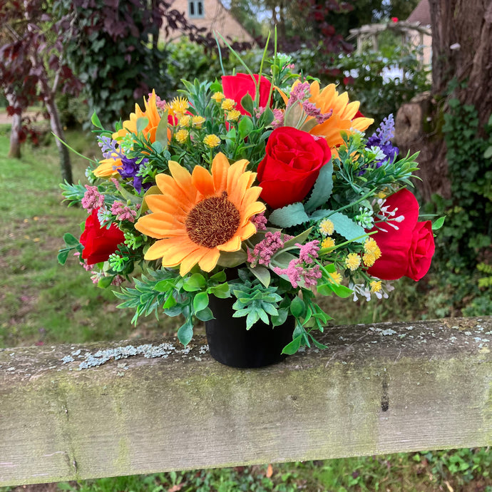 A graveside flower arrangement in black pot