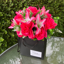 flower arrangement of artificial roses and lilies in black box