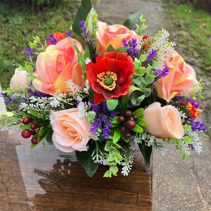 a grave pot with flowers featuring orange and purple artificial silk blooms