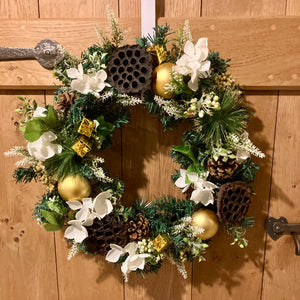 An artificial pine christmas wreath with pale gold and ivory decorations