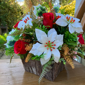 A Christmas artificial flower arrangement in rustic wooden container