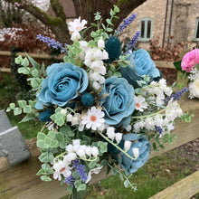 A wedding bouquet of white and teal flowers and foliage