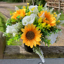 a grave side pot with flowers in shades of yellow and cream
