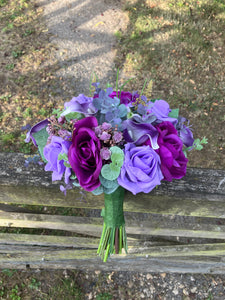 An artificial faux silk wedding bouquet of purple flowers