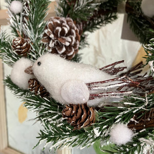 A frosty christmas wreath of artificial fir branches and pinecones with white dove.