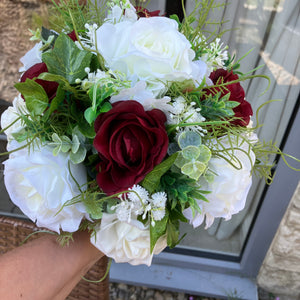 A brides bouquet of deep burgundy and ivory faux flowers