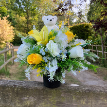 A graveside flower arrangement with teddy in black pot