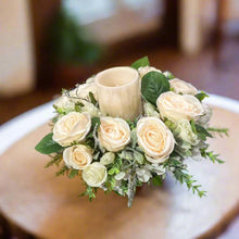 A table centrepiece of ivory flowers, foliage & led candle