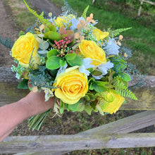 A brides bouquet of roses, peonies and fern