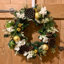 An artificial pine christmas wreath with pale gold and ivory decorations