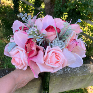 A wedding bouquet of coral and grey artificial roses and orchids