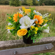 a grave side pot with flowers in shades of yellow and cream