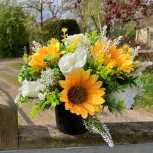 a grave side pot with flowers in shades of yellow and cream