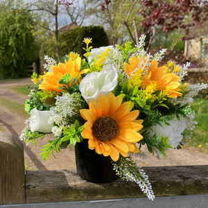 a grave side pot with flowers in shades of yellow and cream