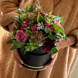 A flower arrangement in black hat box