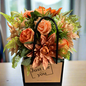 A handtied bouquet featuring artificial flowers in black bag