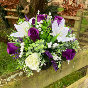 a grave side pot with flowers in shades of purple and cream