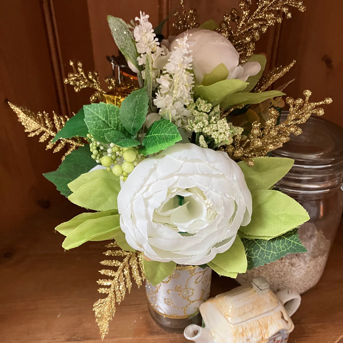 artificial white and gold Christmas flowers arrangement in glass bottle