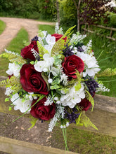 A wedding bouquet of artificial silk burgundy & ivory flowers, foliage & berries