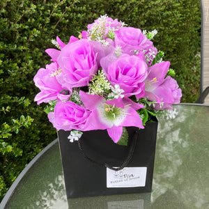 flower arrangement of artificial roses and lilies in black box