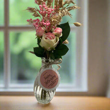 A posy of dried pink grasses and silk rose flowers in glass bud vase