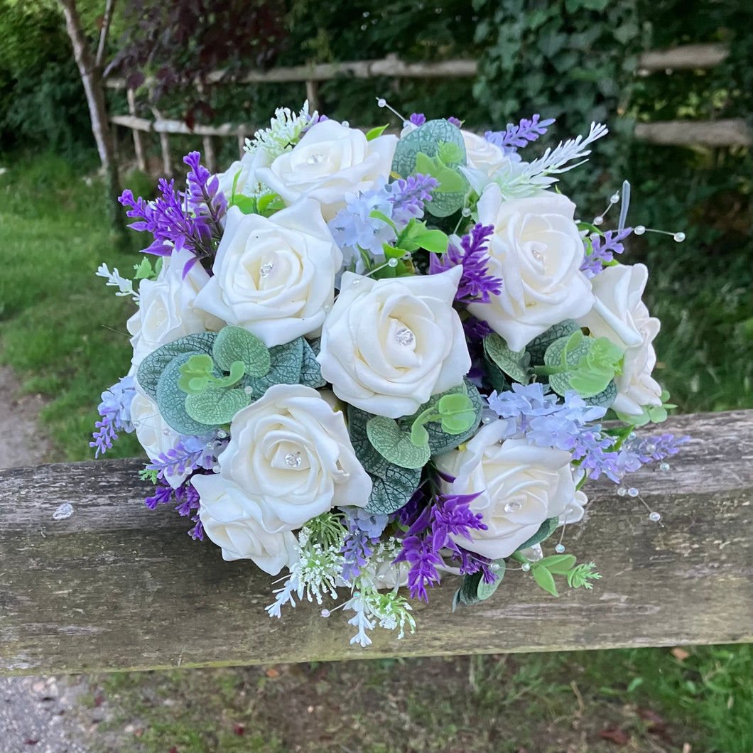 A wedding bouquet of artificial ivory roses & lavender flowers
