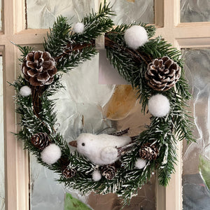 A frosty christmas wreath of artificial fir branches and pinecones with white dove.