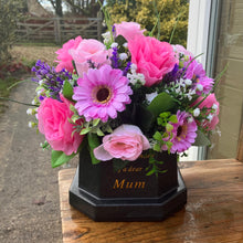 Pink and lilac memorial flowers arranged in black plastic pot