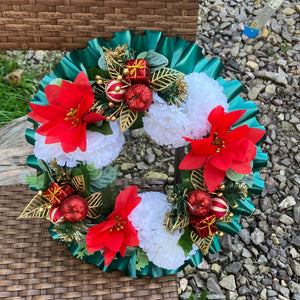 a memorial christmas wreath featuring baubles, cones and poinsettia