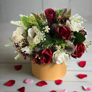 Gold hat box with artificial roses and thistle flowers