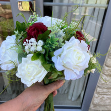 A brides bouquet of deep burgundy and ivory faux flowers