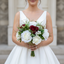 A brides bouquet of deep burgundy and ivory faux flowers