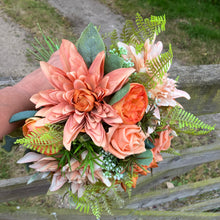A brides bouquet featuring dahlia, ranunculas and roses
