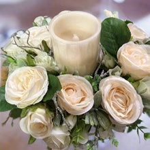 A table centrepiece of ivory flowers, foliage & led candle