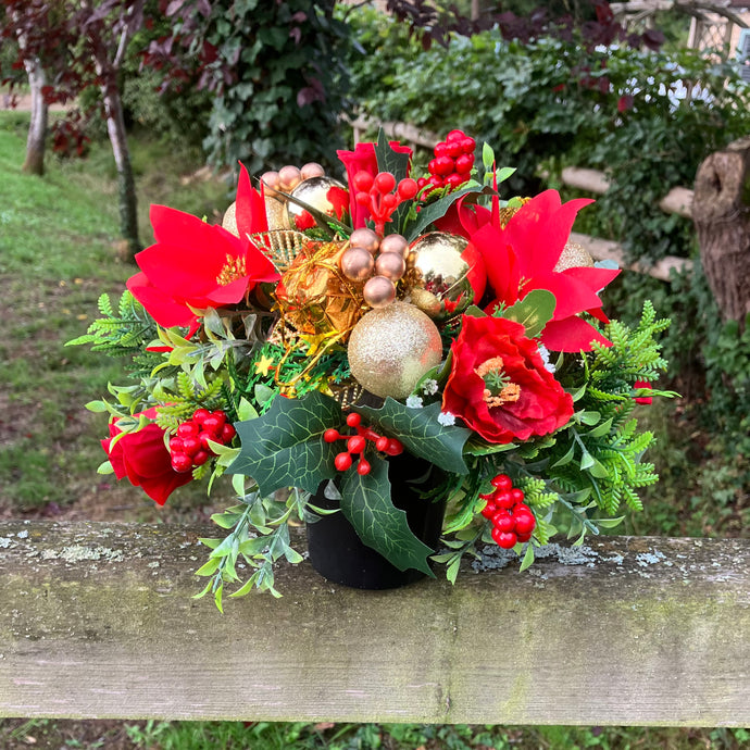 a christmas grave side memorial pot with red artificial flower arrangement