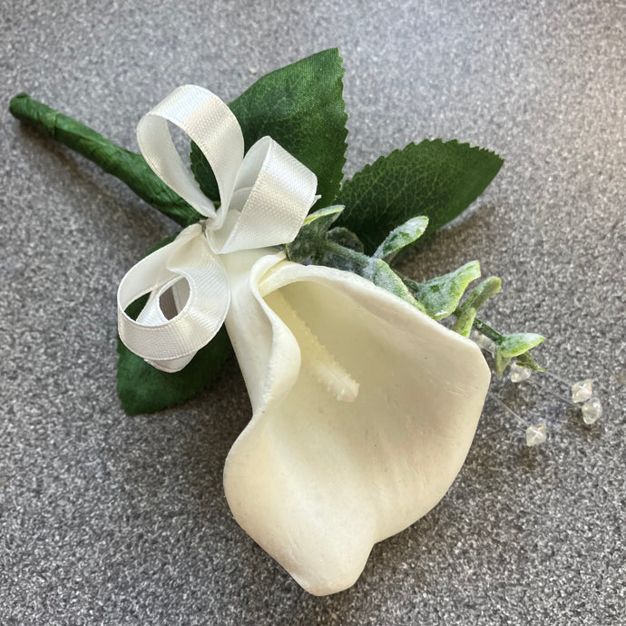 A buttonhole of a white real touch calla lily and bow