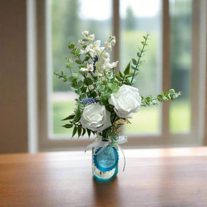 artificial blue and white flowers in glass bud vase