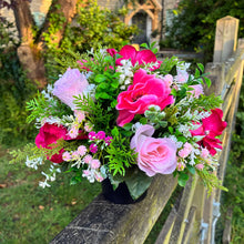 a graveside pink and cream memorial arrangement in black plastic pot