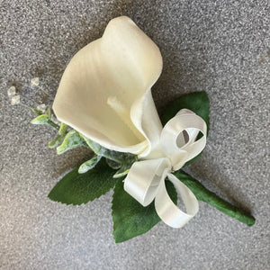 A buttonhole of a white real touch calla lily and bow