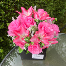 flower arrangement of artificial roses and lilies in black box