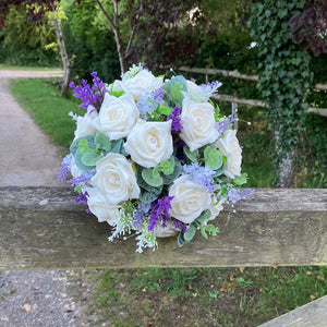 A wedding bouquet of artificial ivory roses & lavender flowers