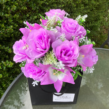 flower arrangement of artificial roses and lilies in black box
