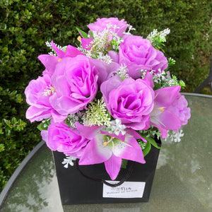 flower arrangement of artificial roses and lilies in black box