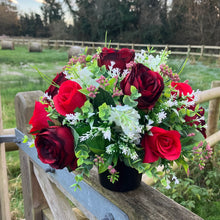a graveside pot with a red and white artificial silk flower arrangement